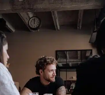 Photo of a Man with Curly Hair Holding a Glass of Beer