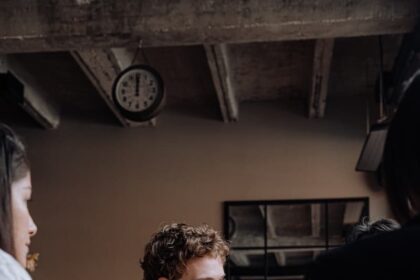 Photo of a Man with Curly Hair Holding a Glass of Beer