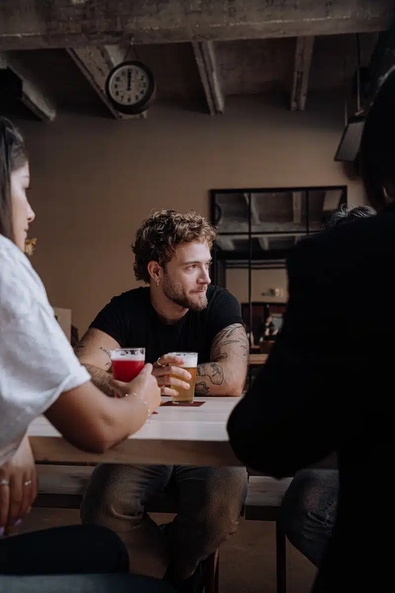 Photo of a Man with Curly Hair Holding a Glass of Beer
