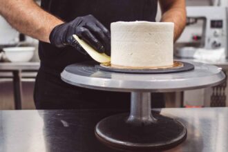Pâtissier utilisant un plateau tournant pour lisser un gâteau décoré